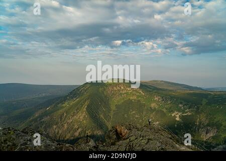 Un sommet de montagne vert avec de beaux nuages et le soleil piquant. Banque D'Images