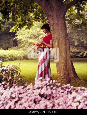 FEMME AFRO-AMÉRICAINE DES ANNÉES 1970 TENANT LE PANIER DE FLEURS PORTANT LE BIAIS DU HAUT ROUGE COUPER LA JUPE MAXI S'APPUYANT CONTRE L'ARBRE JARDIN ARRIÈRE - KG9039 BUC001 HARS STYLE DE VIE FEMMES MOODY MAISON VIE NATURE COPIER L'ESPACE CONTRE DEMI-LONGUEUR DAMES PENSIVE PERSONNES RÉFLÉCHIS INSPIRATION SÉRÉNITÉ TROUBLÉE TRISTESSE STYLES AFRO-AMÉRICAINS RÉFLEXION AFRO-AMÉRICAINE PENSE NOIR L'HUMEUR ETHNIQUE REFLÉTANT MÉDITER RÉFLÉCHIR À LA PERTE DANS LA PENSÉE GLUM ÉLÉGANT MÉDITER CONTEMPLATIF MÉDITER MODE JEUNE FEMME ADULTE MÉDITATIVE MISÉRABLE CONSIDÉRANT LES AFRO-AMÉRICAINS À L'ANCIENNE Banque D'Images