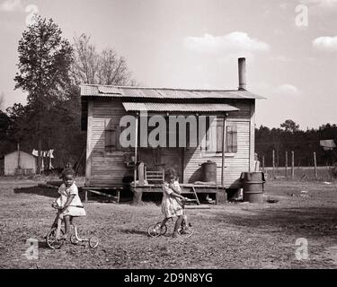 DANS LES ANNÉES 1950, DEUX FILLES AFRO-AMÉRICAINES SONT PIEDS NUS ET SONT À CHEVAL SUR DES TRICYCLES DANS LA COUR AVANT DE LA MAISON RURALE SHACK - N592 HAR001 HARS VIE À LA MAISON ÉTATS-UNIS COPIER ESPACE AMITIÉ DEMI-LONGUEUR RÉSIDENTIEL ÉTATS-UNIS DE AMERICA BUILDINGS SIRS BICYCLES SŒURS B&W BIKE TRISTESSE AMÉRIQUE DU NORD L'AMÉRIQUE DU NORD RÊVE PROPRIÉTÉ AFRO-AMÉRICAINE RÉCRÉATION ANCIENNE FIERTÉ DU SUD PIEDS NUS MAISONS SHACK FRÈRES ET SŒURS SUD IMMOBILIER STRUCTURES RÉSIDENCE DÉSAVANTAGÉ EDIFICE LES DÉÇUS DÉÇUS DÉSAFFECTÉS ONT DÉCONNECTÉ LES JEUNES PAUVRES TOGETHNESS NOIR ET BLANC DISTRAUGHT HAR001 TRICYCLES À L'ANCIENNE Banque D'Images