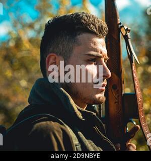 Chasseur avec fusil de chasse. Chasseur pendant la saison de chasse de l'automne. Homme tenant le fusil. Chasse au cerf. Gros plan Portrait d'un chasseur de hamdsome. Banque D'Images