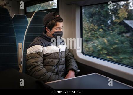 6 novembre 2020 , Londres , Royaume-Uni- adolescent garçon portant un masque de visage dans les transports publics, train du Sud pendant le second Lockdown. Banque D'Images