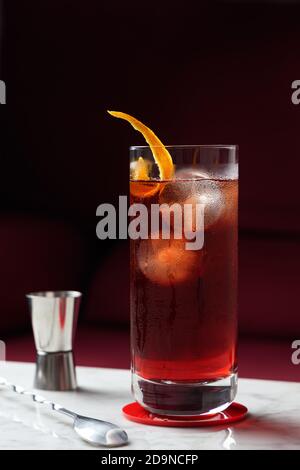 Cocktail Americano avec rotation orange sur une table en marbre. Canapé rouge comme arrière-plan. Vue avant Banque D'Images