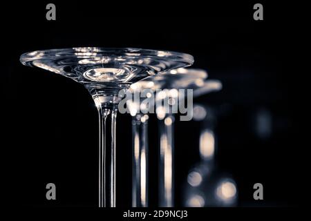 Détail de trois verres debout à l'envers sur un fond sombre . Photographie en noir et blanc Banque D'Images