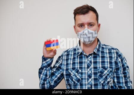 Homme en chemise à carreaux montrer carte drapeau Arménie en main, porter un masque de protection isolé sur fond blanc. Concept du coronavirus dans les pays asiatiques. Banque D'Images