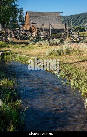 L'ancienne grange en bois et les coraux de la propriété John Molton sur Mormon Row dans le parc national de Grand Teton avec la chaîne de Teton derrière. Wyoming, États-Unis. Banque D'Images