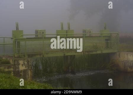Brouillard épais en début de matinée sur une petite rivière avec un déversoir, automne en Allemagne Banque D'Images