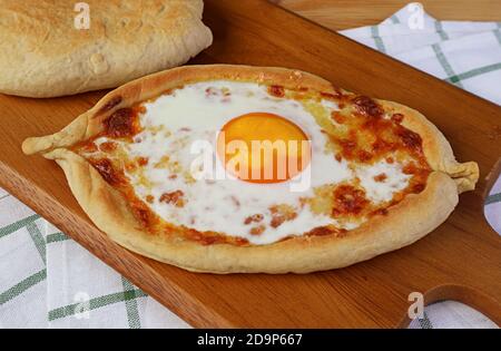 Adjarian Khachapuri maison, fromage et pain géorgien frais aux œufs sur un plateau de bois Banque D'Images