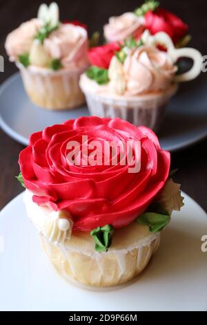 Gros plan sur un délicieux gâteau de rose rouge givrant avec un autre flou petits gâteaux en arrière-plan Banque D'Images