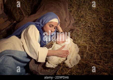 Scène de fête de Noël en direct dans une ancienne grange - Reactment jouer avec des costumes authentiques. Le bébé est une poupée. Banque D'Images