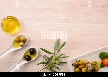 Différentes variantes d'olives à manger et d'huile dans des récipients sur banc de cuisine en bois. Vue de dessus. Banque D'Images