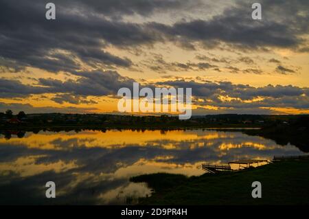 Magnifique coucher de soleil coloré au-dessus d'un lac. Rayons crépusculaires et nuages reflétés dans l'eau calme Banque D'Images