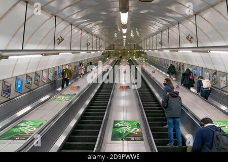 LONDRES, ANGLETERRE - 23 OCTOBRE 2020 : escaliers mécaniques du métro de Londres à la gare de Holborn pendant les heures de pointe, avec les passagers portant un masque facial Banque D'Images