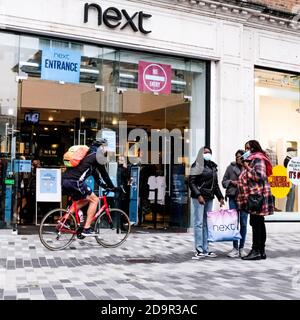 Les acheteurs à l'extérieur D'UN magasin de mode Next High Street pendant COVID-19 Coronavirus portant des revêtements protecteurs pour le visage Banque D'Images