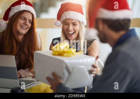 une collègue caucasienne agréablement surprise a pris un cadeau de noël emballé porter un chapeau de père noël Banque D'Images