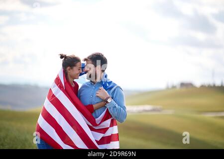 Un couple amoureux dans des moments romantiques vêché par le drapeau américain à la prairie sur une belle journée ensoleillée. Concept d'élection, de campagne, de liberté Banque D'Images