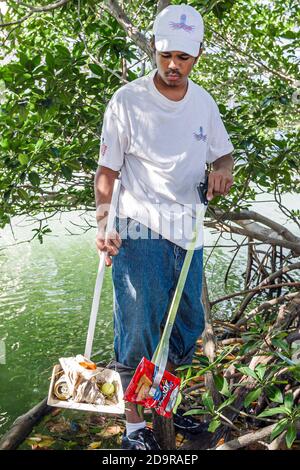Miami Beach Floride, adolescents adolescents adolescents bénévoles du Job corps, Noir Africain garçon remplissant un sac à ordures, nettoyer nettoyage Tatum Waterway déchets l Banque D'Images