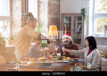 Homme barbu d'âge moyen versant du champagne dans des flûtes de famille membres Banque D'Images
