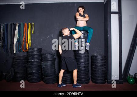 Séances d'entraînement et exercices pour les femmes enceintes dans la salle de sport. Les athlètes caucasiens bodybuilders, couple mari et femme aiment la grossesse et posant après Banque D'Images