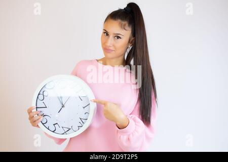 Femme souriante tenant la grande horloge, isolée sur fond blanc. Portrait d'une femme montrant une grande horloge. Banque D'Images