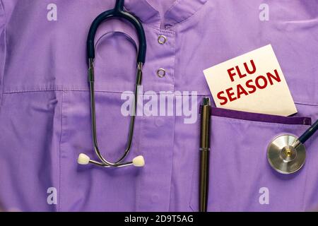 Uniforme médical, carte blanche avec mots saison de la grippe, stylo métalique et stéthoscope. Concept médical. Banque D'Images