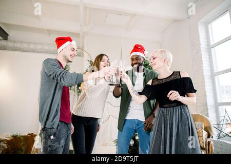 Groupe de jeunes amis multiraciaux à Santa Hats à New Fête de la veille de l'année pour faire un toast levant des verres de champagne Banque D'Images