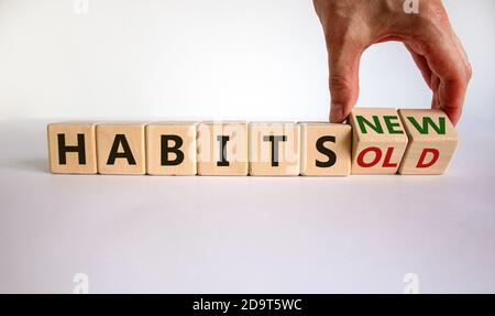 Main masculine tournant un cube et change l'expression « anciennes habitudes » en « nouvelles habitudes ». Belle table blanche, fond blanc. Concept. Copier l'espace. Banque D'Images