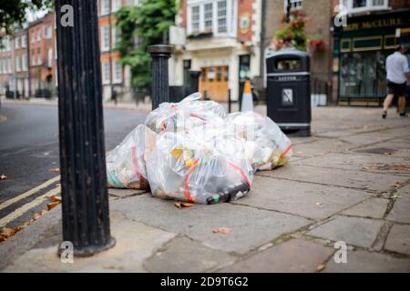 Sacs en plastique de déchets abandonnés sur le trottoir à côté de Un lampadaire Banque D'Images