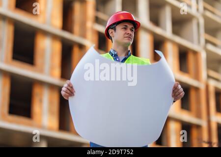 Gros plan des ingénieurs travaillant sur un chantier de construction tenant un modèles Banque D'Images