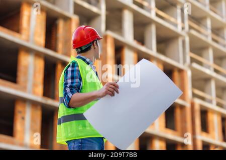 Gros plan des ingénieurs travaillant sur un chantier de construction tenant un modèles Banque D'Images