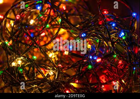 Guirlande de Noël scintillante. Des voyants lumineux s'allument sur fond sombre Banque D'Images