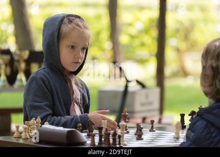 Smart Girl, de 7 ans, participe à un tournoi d'échecs pour enfants en plein air dans le parc. Banque D'Images