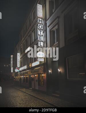 Panneau fluorescent blanc au néon indiquant « Hotel » à la lumière rouge de Hambourg district Banque D'Images