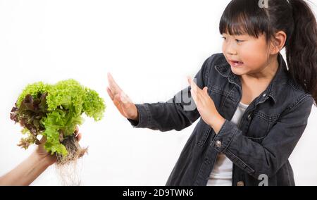 La salade que les enfants n'aiment pas la fille Asianis tenant une salade verte qu'il n'aime pas, saine et bonne pour un fond blanc. Banque D'Images