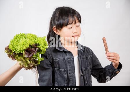 La salade que les enfants n'aiment pas la fille Asianis tenant une salade verte qu'il n'aime pas, saine et bonne pour un fond blanc. Banque D'Images