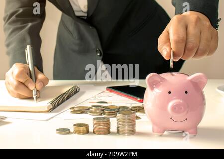 Gros plan d'une femme d'affaires tenant une pièce dans une banque de pigey, un concept d'économiser de l'argent pour la comptabilité financière. Banque D'Images
