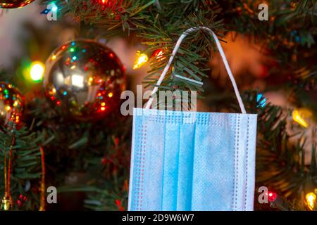 Gros plan sur un masque médical accroché à un arbre de Noël. Concept: Pandémie, covid -19, coronavirus pendant les vacances de Noël Banque D'Images