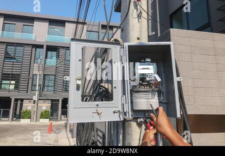 Un électricien est en mesure de configurer un compteur pour mesurer la consommation d'électricité dans la boîte sur le poteau. Banque D'Images