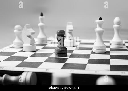 Un pion noir se tient contre un plateau entier de pièces d'échecs blanches, foyer sélectif, espace de copie. Le concept est un contre tous. Concept de leadership parmi les concurrents Banque D'Images