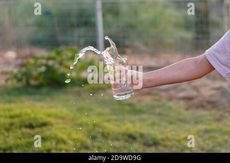 une fille déborde d'eau du verre Banque D'Images