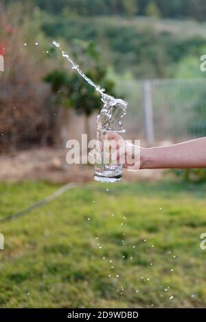 une fille déborde d'eau du verre Banque D'Images