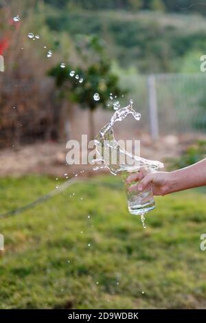 une fille déborde d'eau du verre Banque D'Images