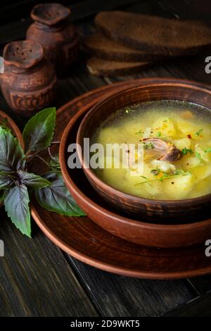 Soupe de perdrix sauvage dans une casserole avec des légumes sur l'ancien arrière-plan en bois Banque D'Images