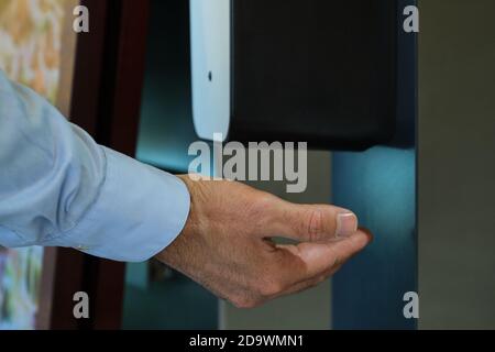 Une main sous le distributeur automatique d'alcool. Pandémie de coronavirus, crise Covid-19. Banque D'Images