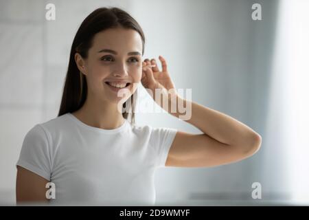 Jeune femme agréable debout à la salle de bains près des oreilles de nettoyage de miroir Banque D'Images