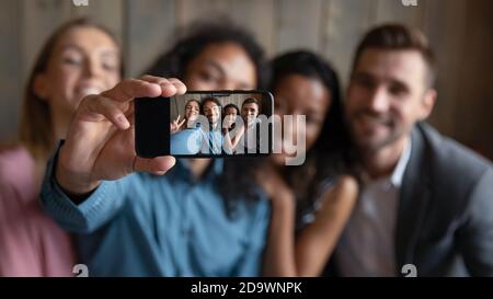 Quatre amis du millénaire multiethniques divers montrant le selfie du spectateur sur un smartphone Banque D'Images