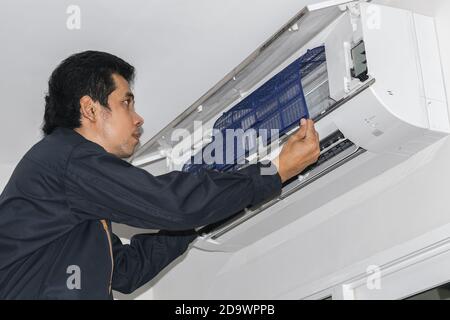 Les réparateurs de climatisation en uniforme bleu vérifient et réparent l'air suspendu au mur. Banque D'Images