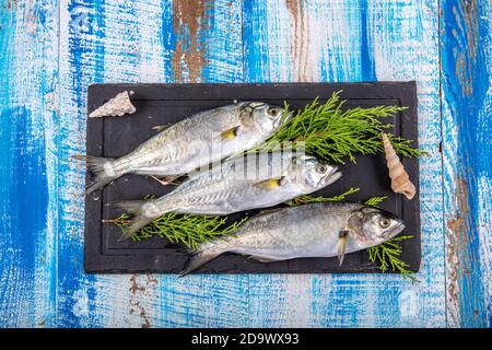 Poisson cru (corégone). Poissons de mer, poissons bleus et citrons sur fond de bois. Banque D'Images