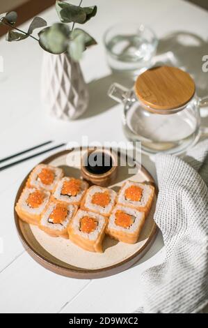 Roulé à sushis avec saumon et caviar. Cuisine japonaise. Des petits pains au saumon et au caviar sont servis sur un fond de bois blanc Banque D'Images