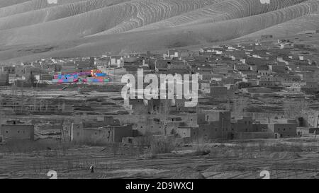 Photo monochrome d'un village berbère dans les montagnes de l'Atlas, au Maroc, avec un seul bâtiment en couleurs (peinture originale). Banque D'Images
