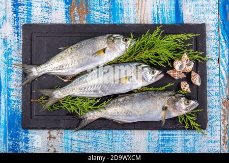 Poisson cru (corégone). Poissons de mer, poissons bleus et citrons sur fond de bois. Banque D'Images